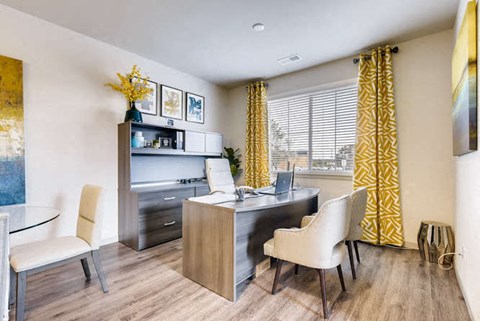 a living room with a desk and chairs and a window